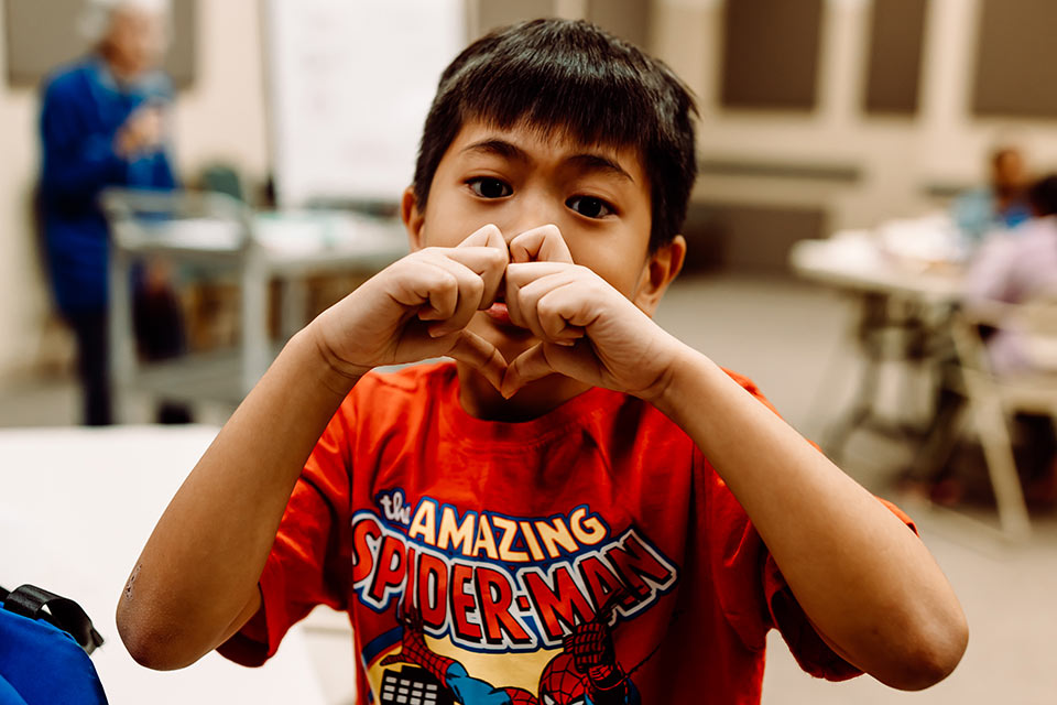 A boy making a heart symbol with his hands