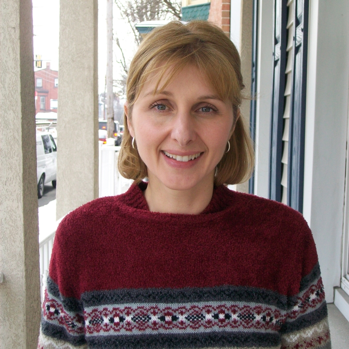 A photo of Julie Baum smiling while standing near a window