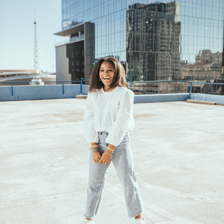 Alena standing and smiling on the top of a high building in the city