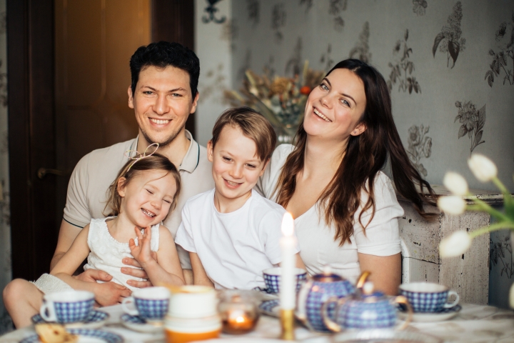 A family of four at the kitchen table smiling