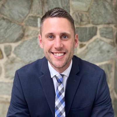 A picture of Zac Bauermaster in a suit smiling at the camera