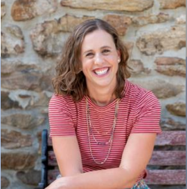 A picture of Lauren Gaines sitting on a bench in front of a stone wall while smiling at the camera
