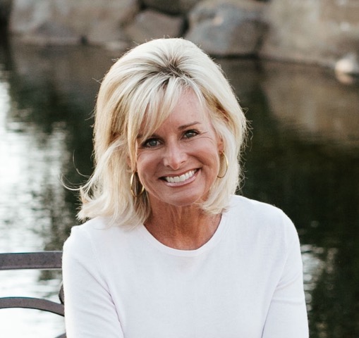 A picture of Jodie Berndt smiling at the camera while sitting near a pond
