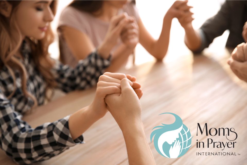 A group of women sitting around a table together praying